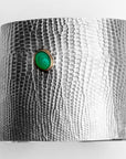 Flat-lay of the Reptilia Maxima silver cuff with green chrysoprase cabochon and snake-scale texture.